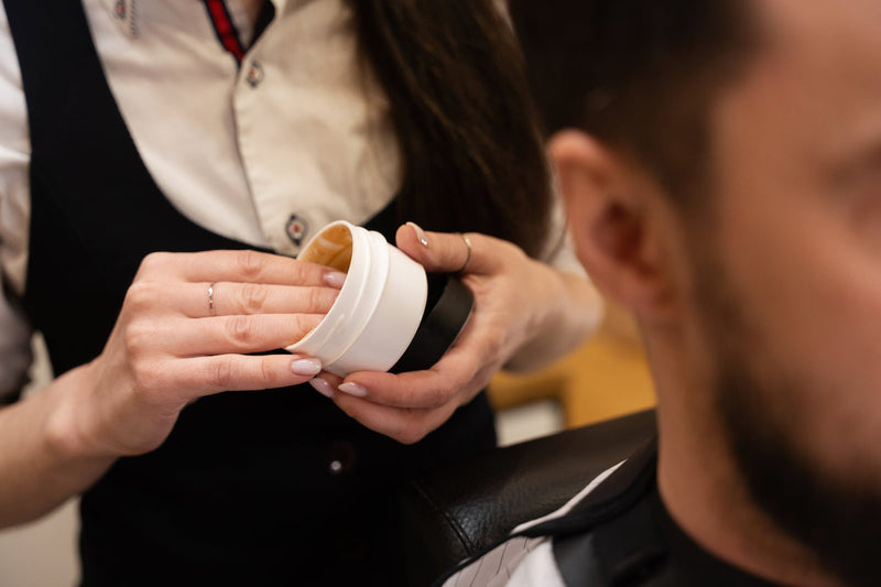 Barber styling a male client’s hair with pomade in a modern barbershop – best hair pomade for men 2025