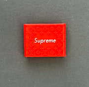 Red Supreme box featuring Louis Vuitton pattern design on a dark background.