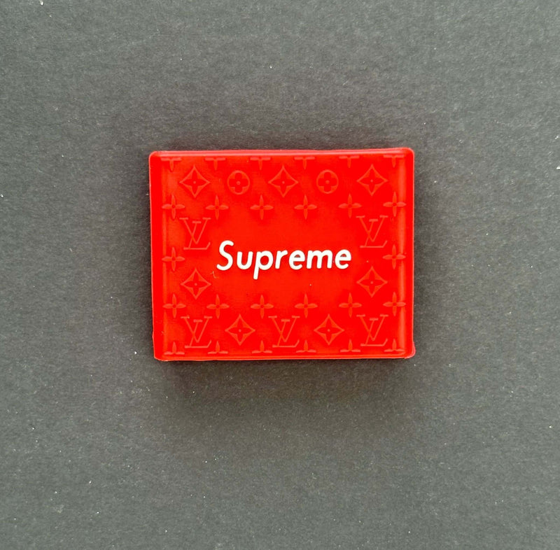 Red Supreme box featuring Louis Vuitton pattern design on a dark background.