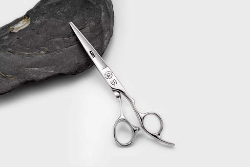 Silver scissors with brand name on a gray background