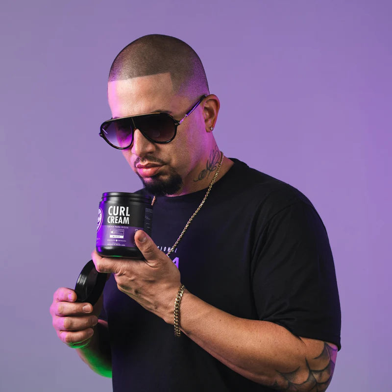 Man holding a container labeled 'Curl Cream' against a purple background